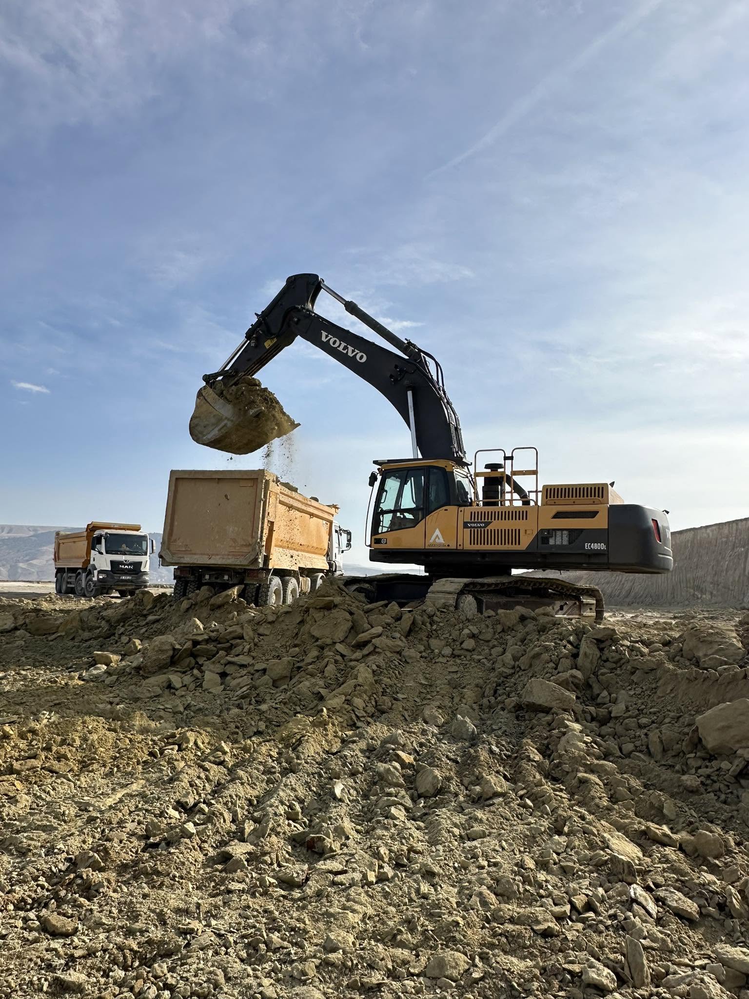 Volvo EC480 paletli ekskavatör sahada damperli kamyona hafriyat yüklüyor.